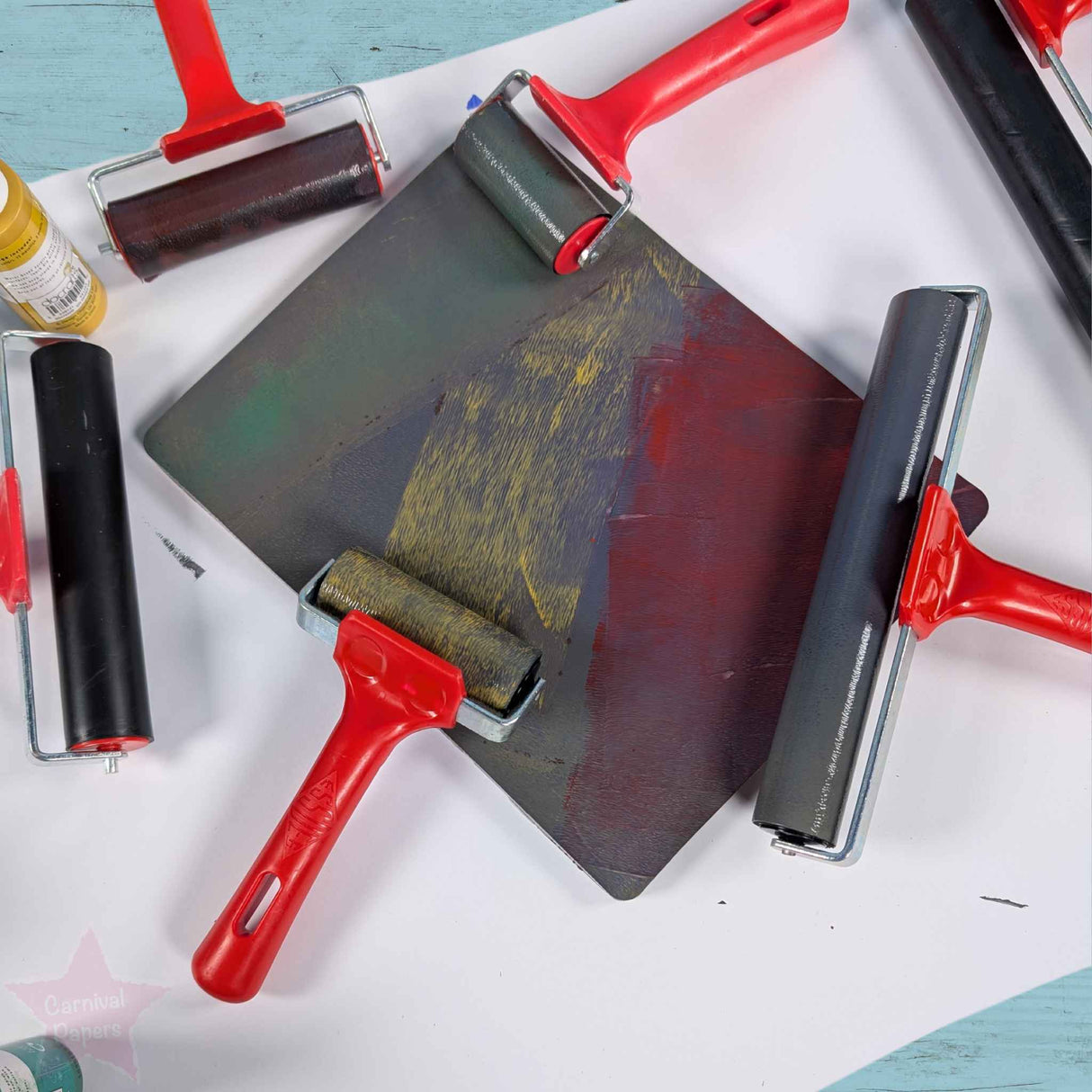 Set of Rollers and a screen printing plate on a white surface with a blue background.
