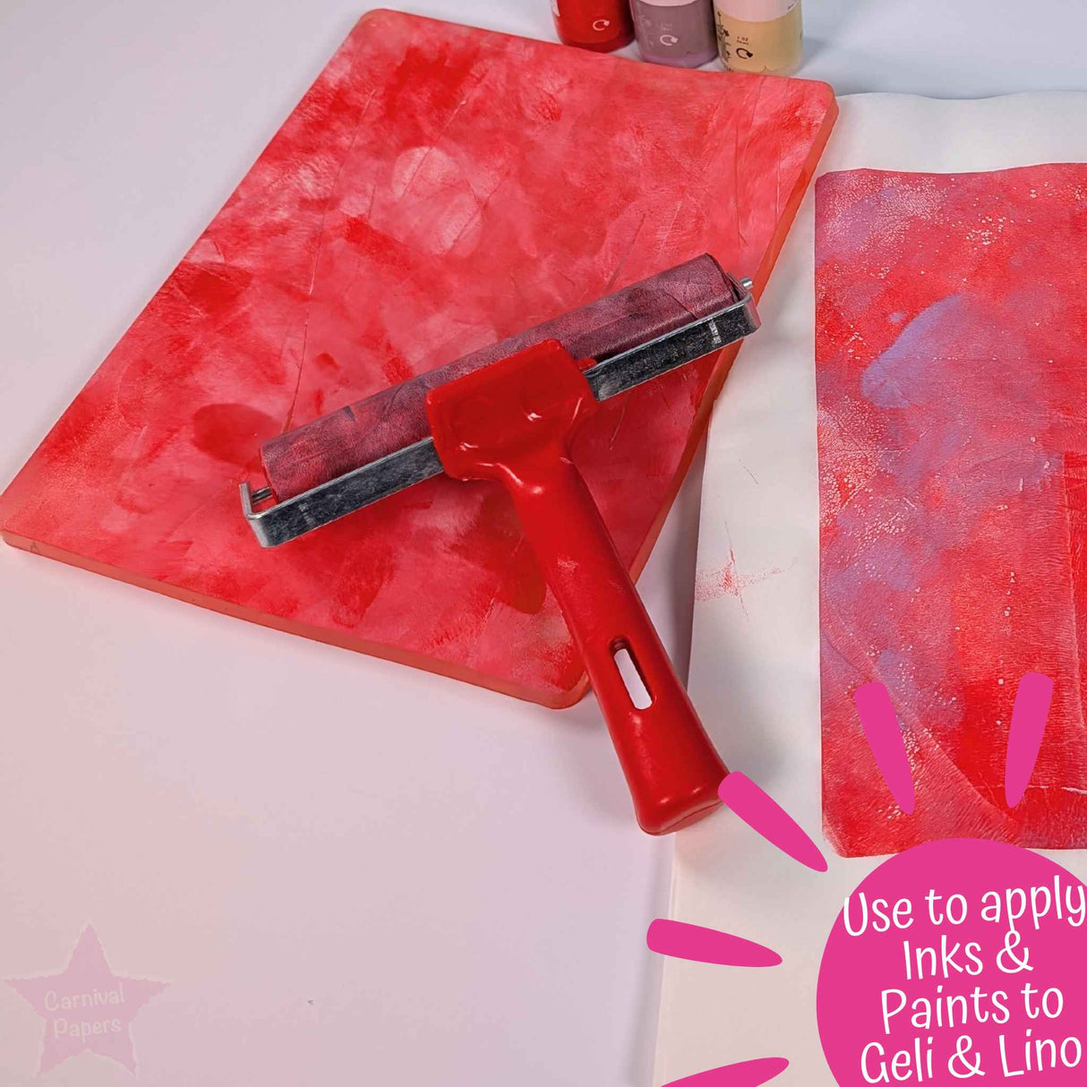 Red brayer roller being used with wet strength tissue paper with pink paint strokes, used to apply inks and paints to geli playe and lino sheets
