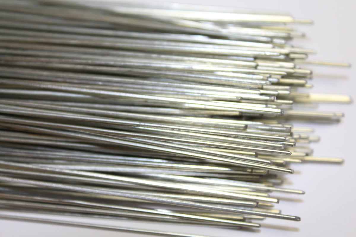 A close-up of many thin metallic silver rods or wires bundled together on a plain white background.