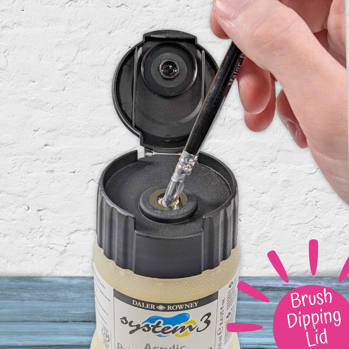 Artist dipping brush into open Daler Rowney System 3 Acrylic Printing Medium pot using the brush-dipping lid.