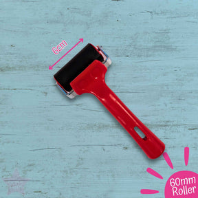 Red roller with black pad on a blue wooden surface, labeled '60mm Roller'.
