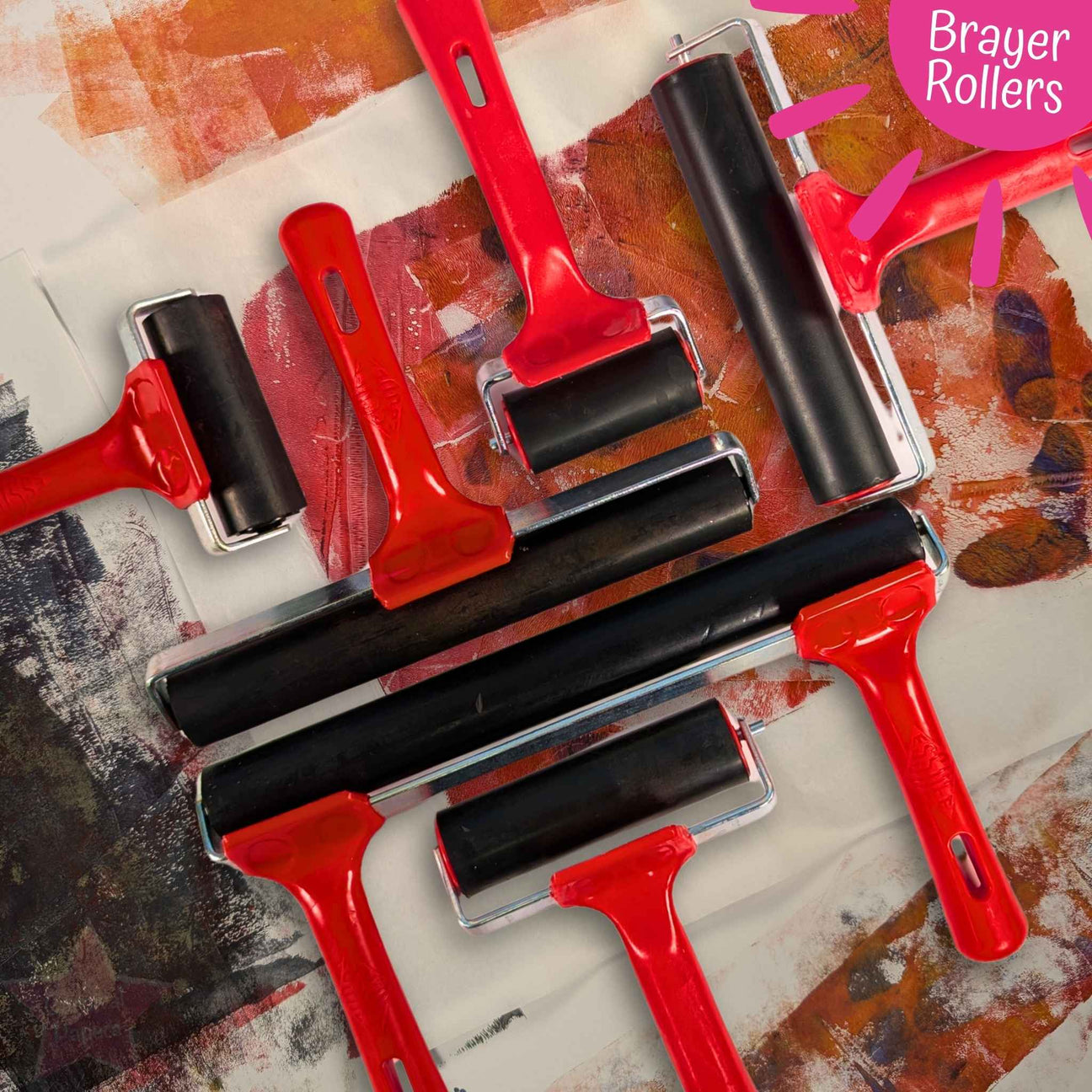 Set of red brayer rollers on a textured surface with 'Brayer Rollers' text.