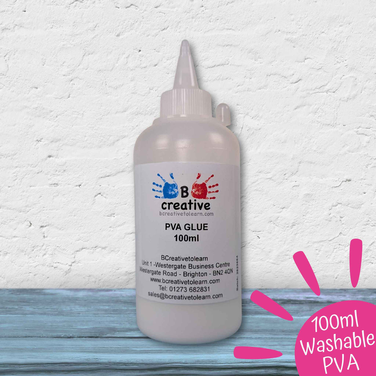 A 100ml bottle of B Creative PVA Glue, 99% washable, shown on a rustic blue wooden surface against a white textured wall. A pink circular badge in the bottom right corner reads '100ml Washable PVA'.